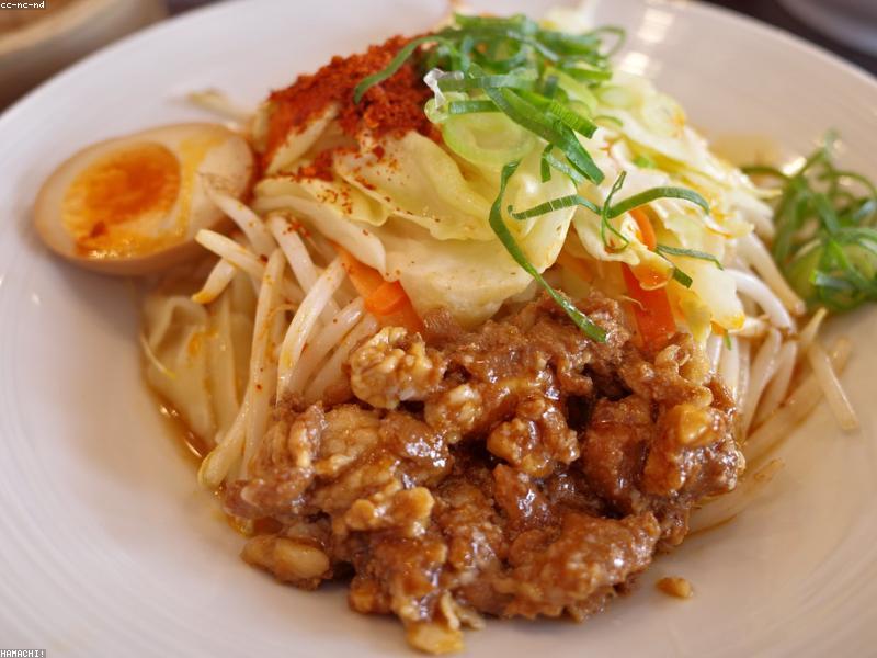 A bowl of hand-pulled noodles in clear broth with green vegetables