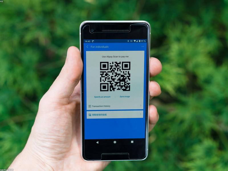 Person scanning QR code for mobile payment at a shop